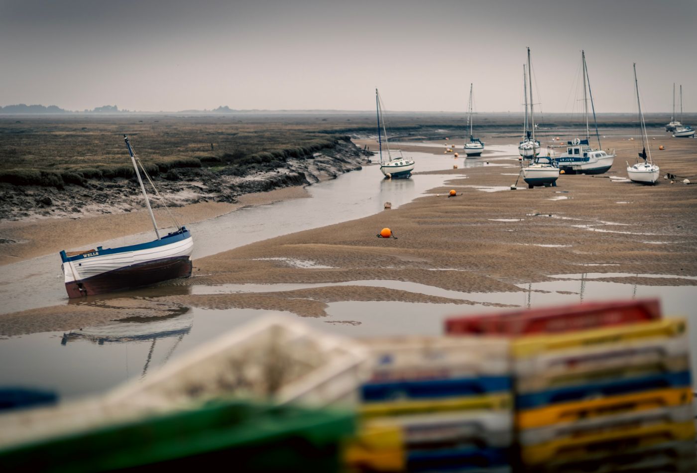 boats sat on the sand in wells next the sea.